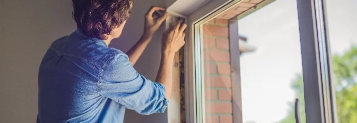 Person bringt Dichtungsband an Fenster an